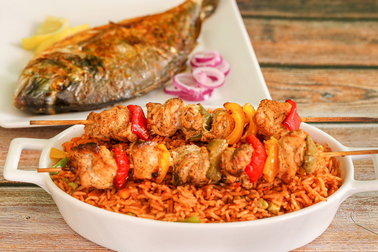 Jollof rice topped with grilled chicken skewers and fried fish, a Calabar Pot signature spread.